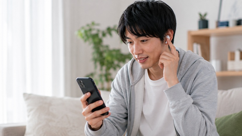 スマートフォンとイヤホンで関西弁の発音を確認する人