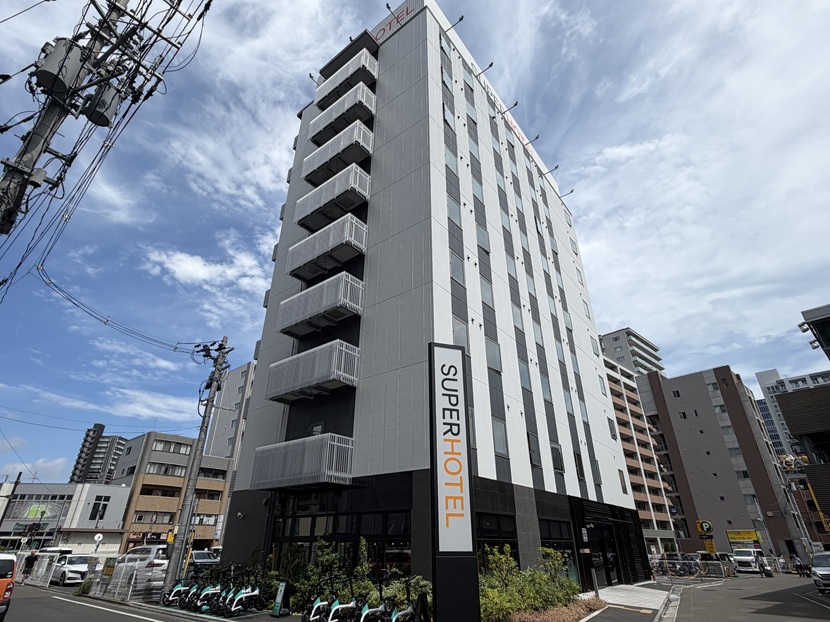 仙台駅近くに建つスーパーホテルの白とグレーの外観と縦長の看板